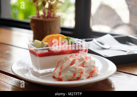 Assorted fruit mousse  cakes with fresh fruit such as grapes, oranges, kiwi and strawberry in coffee shop. Stock Photo