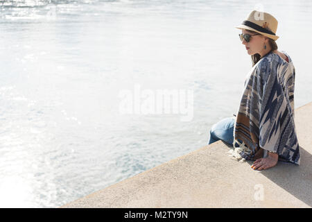 Young woman sits in the harbour promenade of Mannheim, Baden-Wurttemberg, Germany Stock Photo