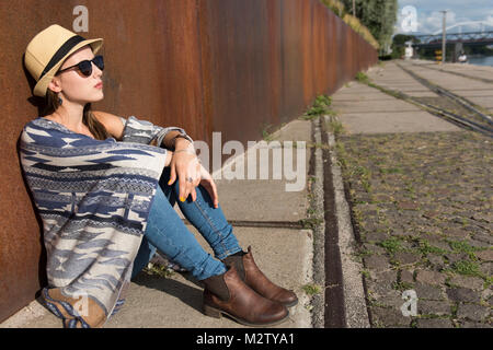 Young woman suns herself outside on the harbour wall Stock Photo