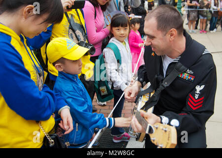 120319-N-SD300-068 HONG KONG (March 19, 2012) Musician 1st Class Brian Nefferdorf, assigned to the U.S. 7th Fleet Band ensemble, Pacific Ambassadors, teaches a boy how to play the banjo while the band performs for 800 people at Hong Kong Disneyland. Sailors from the U.S. 7th Fleet flagship USS Blue Ridge (LCC 19) are in Hong Kong for a port visit. (U.S. Navy photo by Mass Communication Specialist 3rd Class James Norman/Released) US norman mucisian Hong Kong China by #PACOM Stock Photo