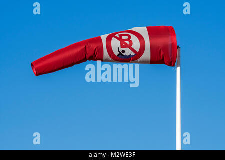 Blowing red and white windsock with no swimming / no bathing notice showing wind direction and speed Stock Photo