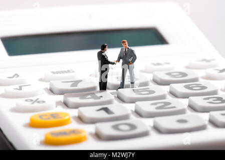 Business concept with two figurines of businessmen standing on calculator Stock Photo