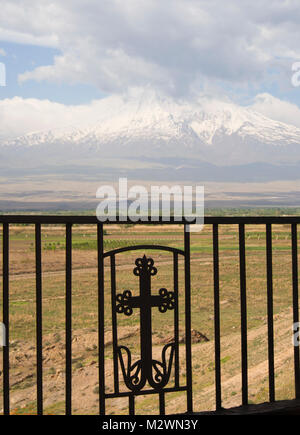 View towards mount Ararat in Turkey from the Armenian side of the border at the Monastery Khor Virap, railing with wrought iron cross Stock Photo