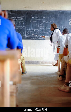 Kibuye/Rwanda - 08/26/2016: Teacher and pupils at mathematics lesson in a classroom in a school in Africa. A blackboard and cross can be seen in the b Stock Photo