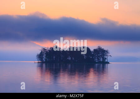 Early morning sunrice at the forest lake with small island, red colors in the sky Stock Photo
