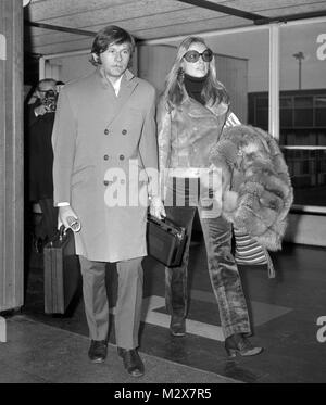 In trouser suit and carrying a fur coat, American-born actress Sharon Tate arrives with her husband Roman Polanski, at Heathrow Airport, London, from Venice to attend the premiere of her film 'Rosemary's Baby'. Stock Photo
