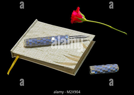 Notepad with pen and red rose on black background Stock Photo