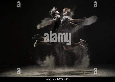Two young dancers jumping in cloud of dust view Stock Photo