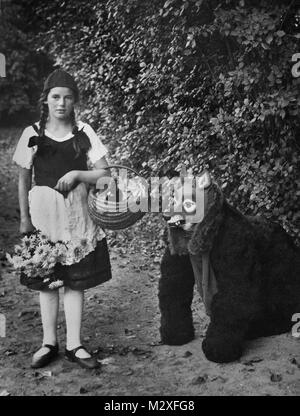 Girl dressed as LIttle Red Riding Hood is confronted by a sorry looking wolf, ca. 1930. Stock Photo