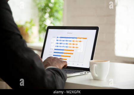 Businessman analyzing monthly stats graph on laptop screen, making annual project financial report data analysis using computer software applications Stock Photo