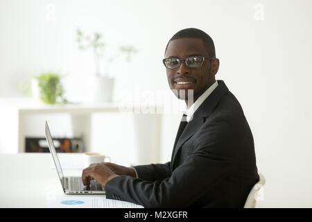 African-american smiling businessman in suit and glasses working on laptop, friendly black financial accountant, marketing manager, business analyst o Stock Photo