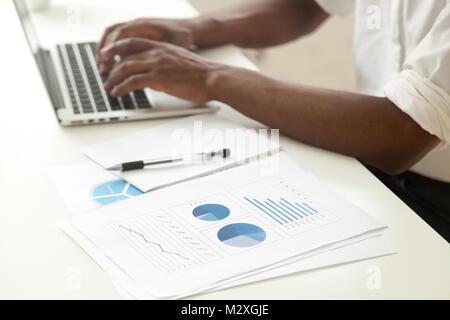 Data analysis and business statistics concept, african-american businessman using laptop analyzing work result infographic stats graphs and charts, ma Stock Photo