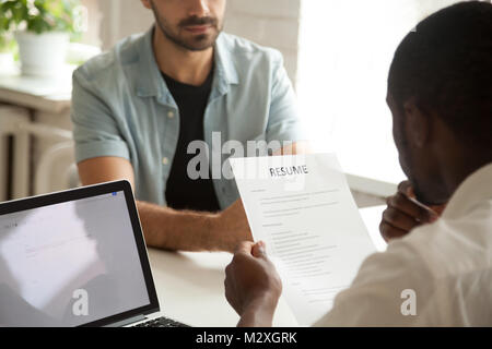 African american hr manager holding applicants curriculum vitae at job interview, black recruiter or employer considering cv of caucasian vacancy cand Stock Photo