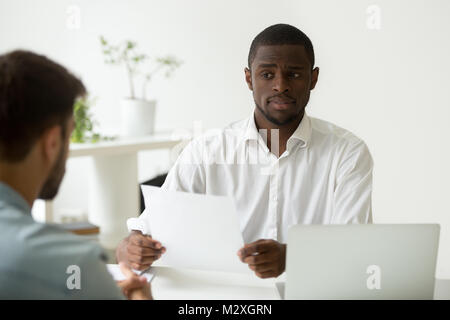 African american hr manager looking doubtful about hiring incompetent candidate, uncertain distrustful black employer skeptical about applicant cv, ba Stock Photo