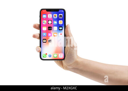 Woman hand holding Apple iPhone X, large screen smartphone, with colorful blue red desktop on its display. The phone is isolated on white background w Stock Photo