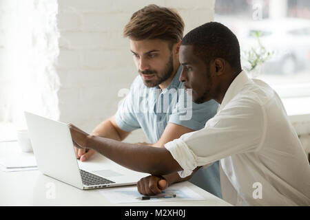 Multiracial project team working together on laptop analyzing on Stock Photo