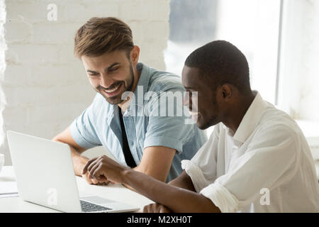 Diverse smiling businessmen having fun laughing working on lapto Stock Photo