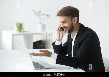 Smiling successful businessman in suit talking on phone using la Stock Photo