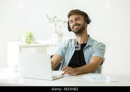 Relaxed young man in headphones enjoying music on laptop  Stock Photo