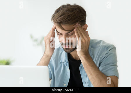 Young man touching temples trying to focus or feeling headache Stock Photo