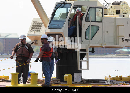 From left: Erik Sherer, James Jarrell, Marc Gutterman, and Dennis Barnes, crew members from the Corps vessel Elizabeth, pause construction on the breakwater to assess their progress. The Elizabeth and its crew are helping to construct a breakwater and oyster reef at the historic fort. Norfolk District partnered with fourth graders from Virginia Beach’s Seatack Elementary School in 2011 to grow baby oysters in floats and then, this spring, create an oyster reef at the fort, where the Norfolk District is located. The reef is an effort to help restore the oyster population and improve the health  Stock Photo