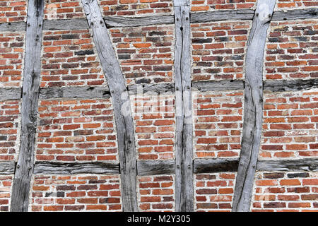 A rustic brick wall with visible wooden beams arranged in a traditional half-timbered style, showcasing the natural textures, bricks and aged wood Stock Photo