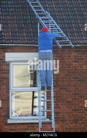 man climbing ladder to undertake roof repairs Stock Photo
