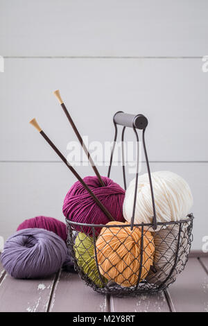 Colorful spring wool yarn in an iron basket with wooden knitting needles. With a copyspace Stock Photo