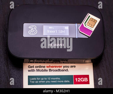 Three data SIM card, holding 12GB of data, which lasts for 12 months, on top of a Huawei portable wifi router, mobile broadband device. England, UK. Stock Photo