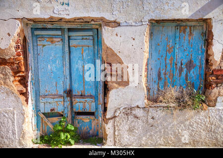 Front view of weathered doors and window in an abandoned city house in Syros island Greece. Stock Photo