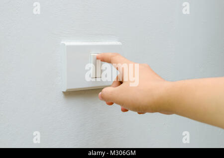 Save electricity Close up of finger is turning on or off on light switch. womans hand with finger on light switch Copy space. Stock Photo