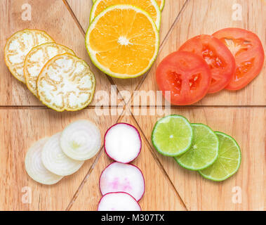 Varied and miscellaneous fruit and vegetables, organized on top of a wooden board, divided and cut, including oranges, eggplant, tomato, onions, lemon Stock Photo