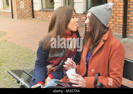 Two girls, asian and European, sit on the bench from the outside. Relax and have fun Stock Photo