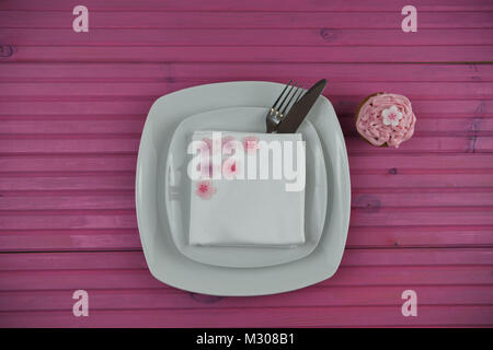 Easter time table place setting in white with cupcake and Easter egg decorations Stock Photo