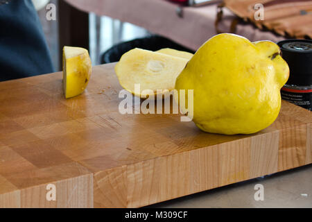 Ripe large yellow quince on wooden cutting board Stock Photo