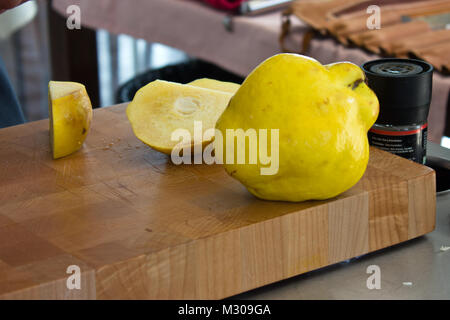 Ripe large yellow quince on wooden cutting board Stock Photo