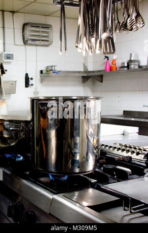 Large steel professional pan on the stove with fire in restaurant kitchen Stock Photo