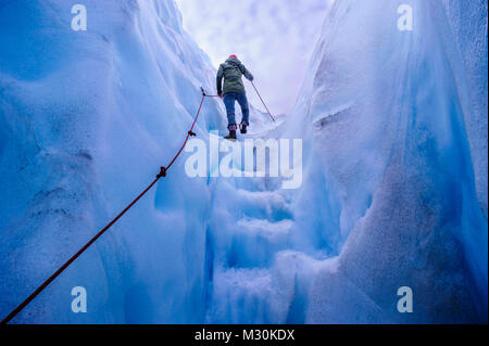 Woman walking steps out of a ice cave in Fox Glacier, South Island, New Zealand Stock Photo