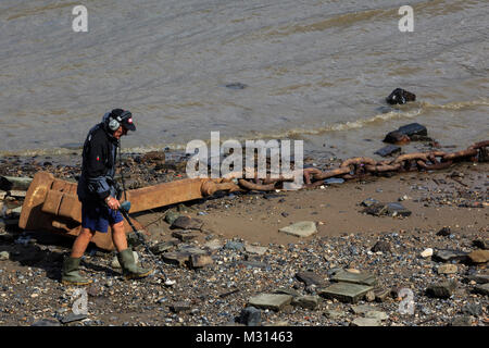 Mudlark with a metal detector looking for hidden treasure on the banks of the River Thames, London, England, United Kingdom Stock Photo