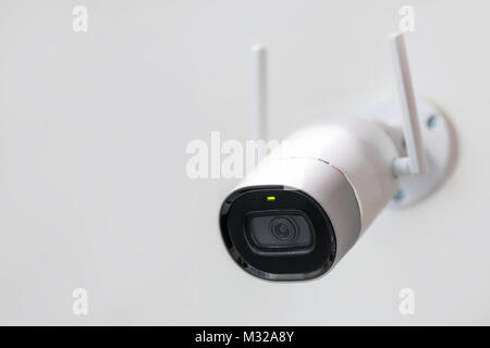 White surveillance camera. CCTV mounted on wall. Wifi wireless antennas enabled. Big brother watching you concept. Stock Photo