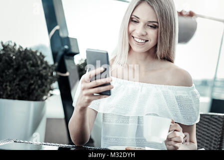 Cheerful nice woman using her smartphone Stock Photo