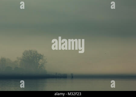 Ioannina lake in Epirus Region, Greece. Artistic panoramic view with natural reflection in the water and fog Stock Photo