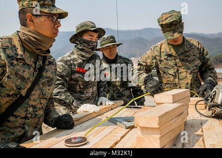 Republic of Korea Marines and U.S. Marines work together to measure out pieces of wood during Korean Marine Exchange Program 16-16 on Camp Rodriguez, South Korea, March 27, 2016.  KMEP provides an opportunity for U.S. Marines to work side-by-side with ROK Marines and help enhance the relationship between both nations. The ROK Marines are with 1st ROK Marine Division and the U.S. Maines are with 9th Engineer support Battalion, 3rd Marine Logistics Group, III Marine Expeditionary Force. (U.S. Marine Corps photo by Cpl. Ryan C. Mains/ Released) US and ROK Marines Working Together During Korean Ma Stock Photo