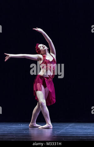 Twelve year old girl performing a solo lyrical dance onstage, doing a fourth position prep with the feet Stock Photo