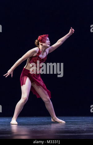 Twelve year old girl performing a lyrical solo dance onstage, doing a sad contracted reach Stock Photo