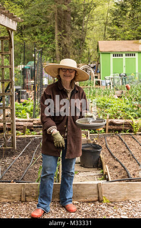 Female gardener taking a break from planting seeds in  springtime in a community garden in Issaquah, Washington, USA Stock Photo