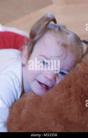 13-month old girl playing with a large stuffed bear.  Bear needs a big hug! Stock Photo