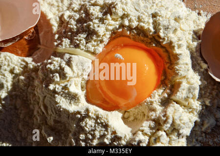 Closeup still life food photography/ Broken egg in the flour on the wooden table Stock Photo