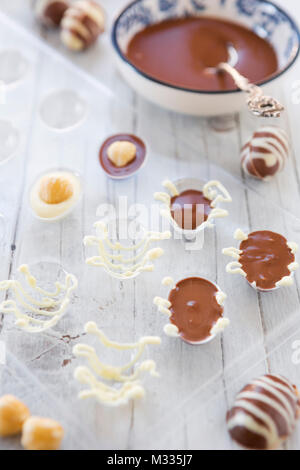 Homemade milk and white chocolate Easter eggs on a rustic table. Stock Photo