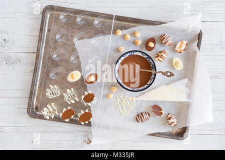 Homemade milk and white chocolate Easter eggs on a rustic table. Stock Photo
